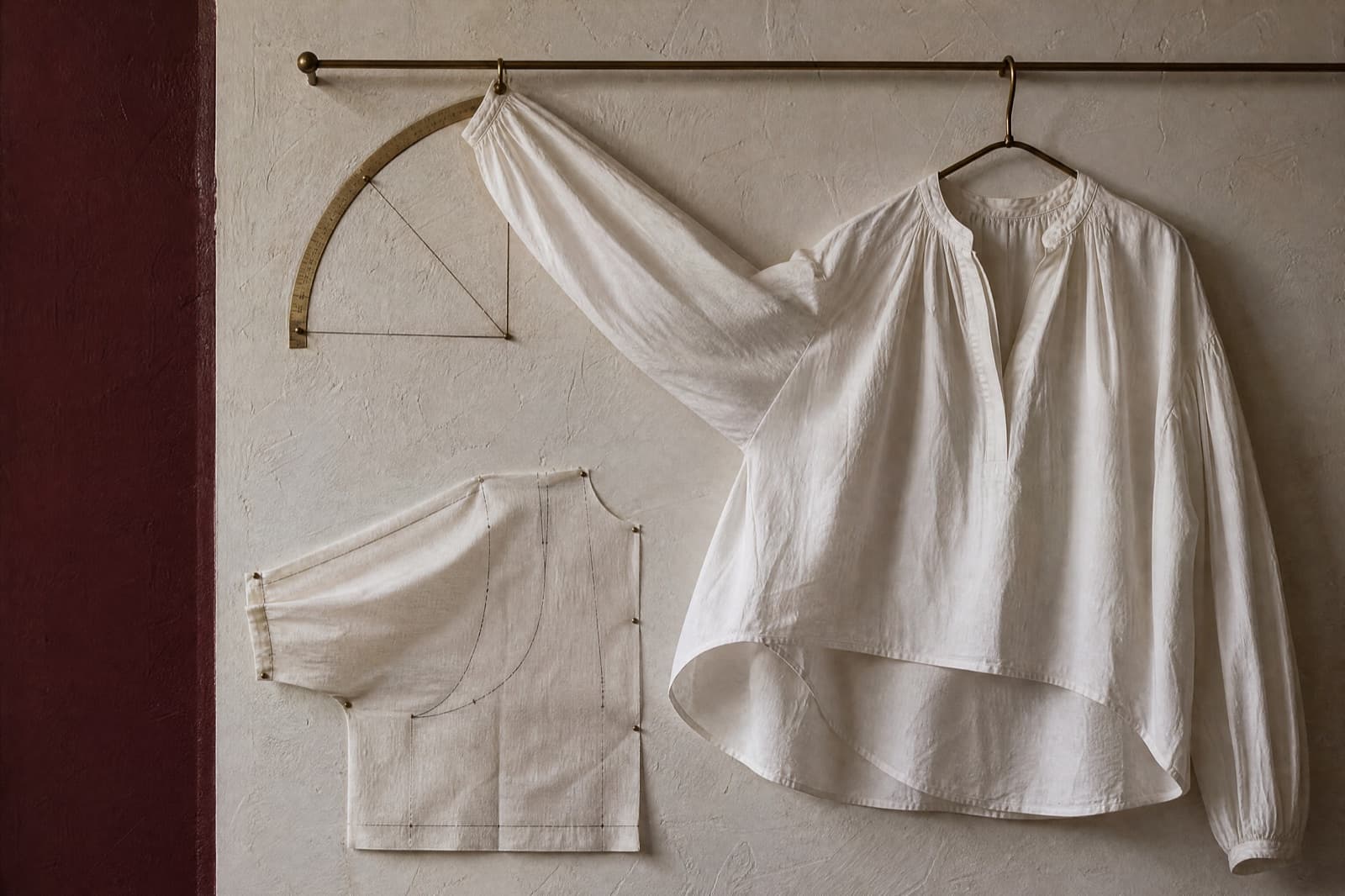 A blouse hung with one sleeve raised against a marked arc, showing the angle at which the hem begins to lift.