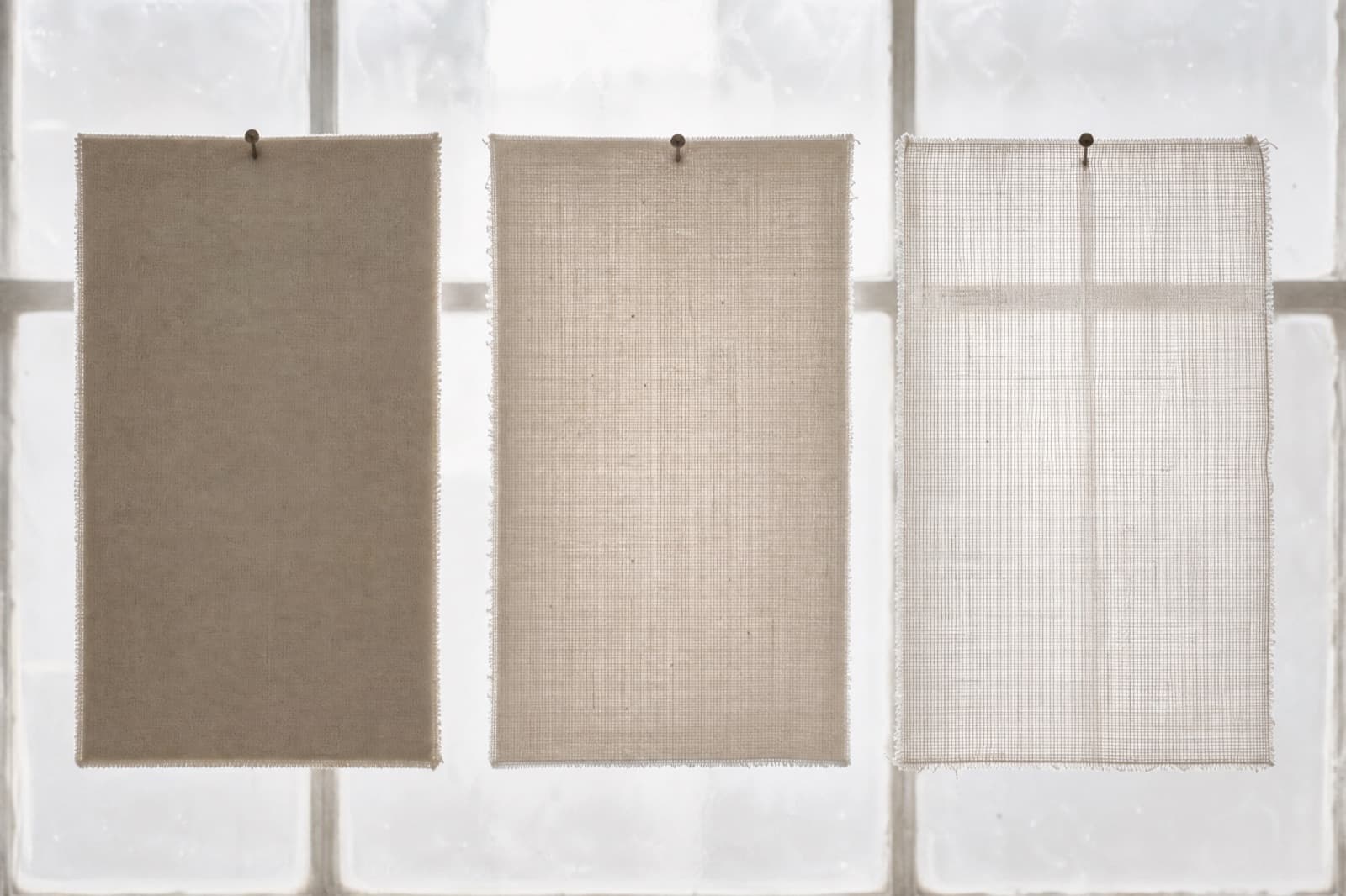 Three swatches of cloth photographed against a bright window, showing the opaque, semi-sheer and sheer steps side by side.