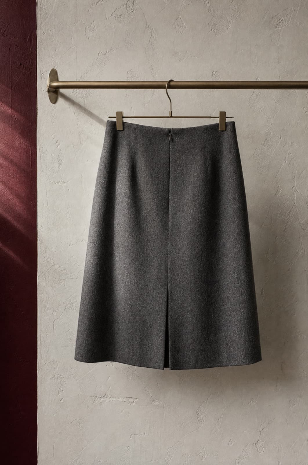 A-Line Skirt, hung from a rail against limestone plaster.