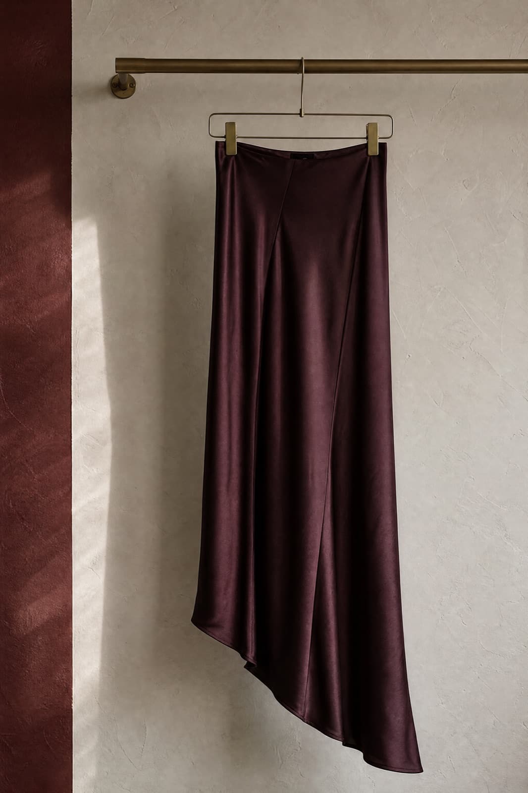 Bias Skirt Long, hung from a rail against limestone plaster.