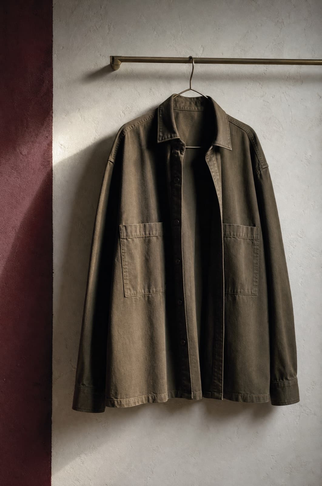 Cotton Overshirt, hung from a rail against limestone plaster.