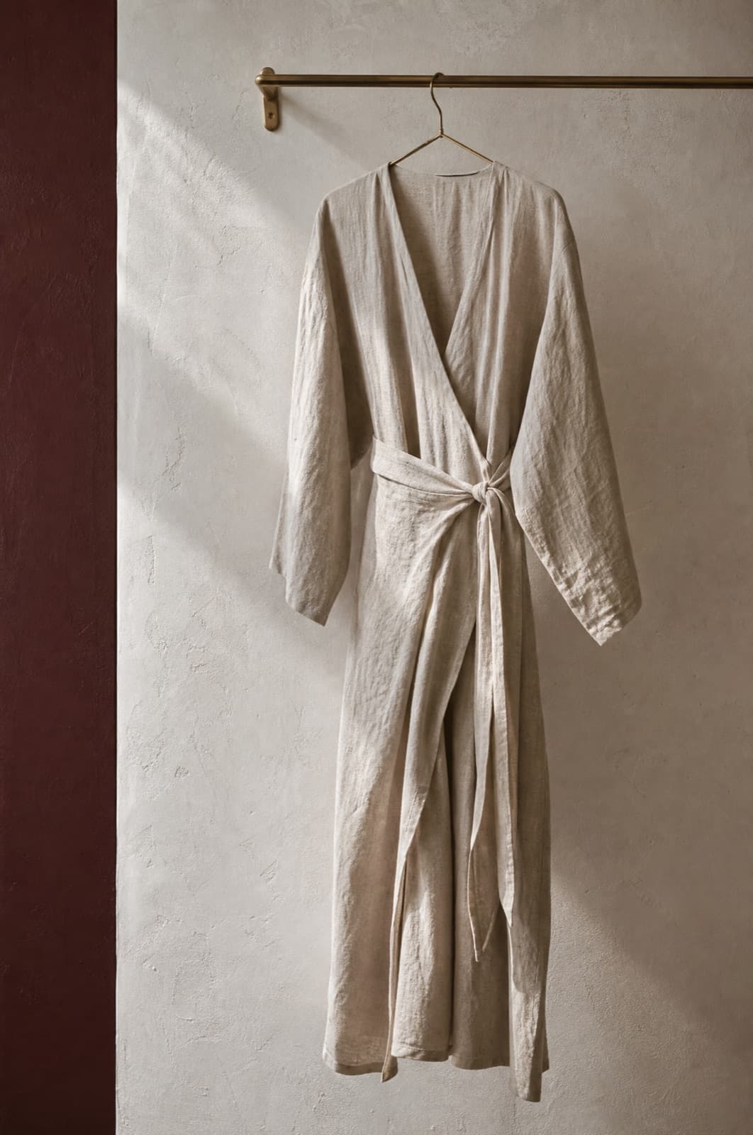 Linen Wrap Dress, hung from a rail against limestone plaster.