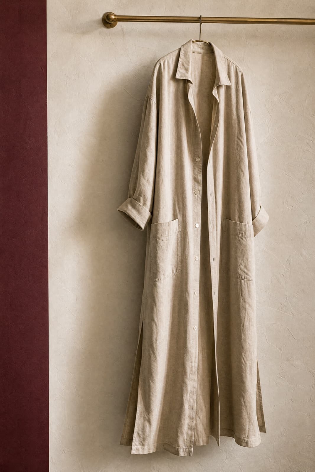 Long Shirt Dress, hung from a rail against limestone plaster.