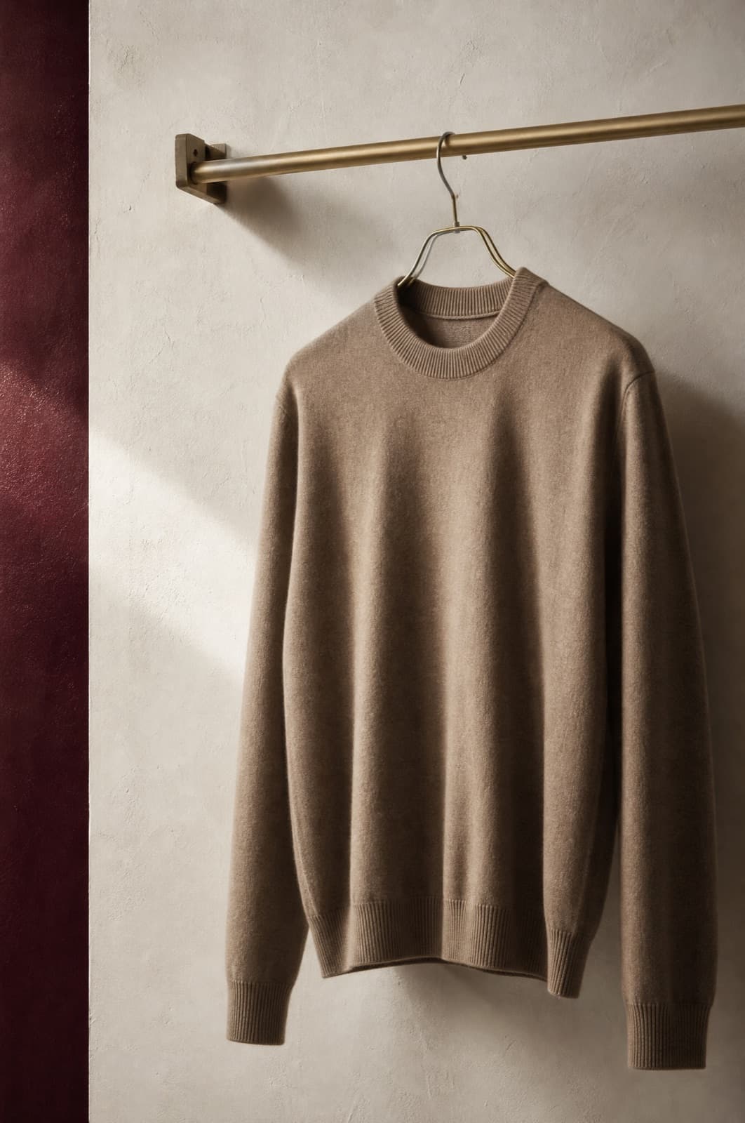 Merino Jumper, hung from a rail against limestone plaster.