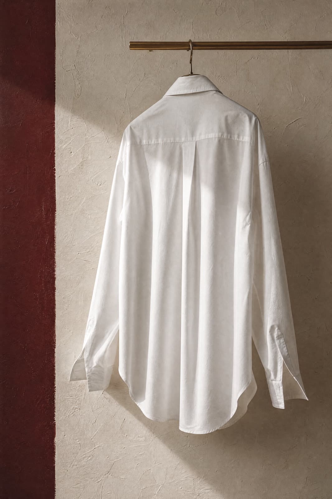 Poplin Blouse, hung from a rail against limestone plaster.