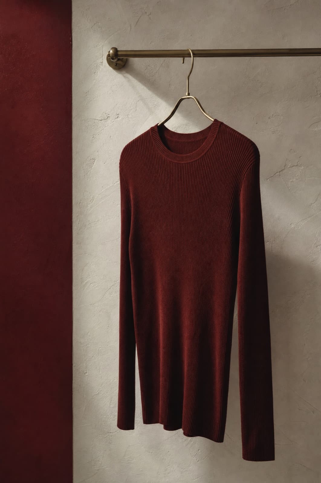 Ribbed Knit Top, hung from a rail against limestone plaster.