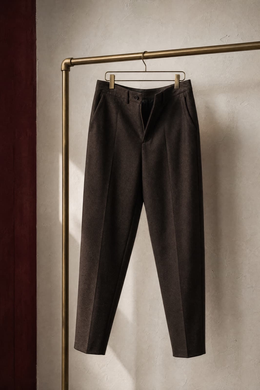 Tapered Trouser, hung from a rail against limestone plaster.