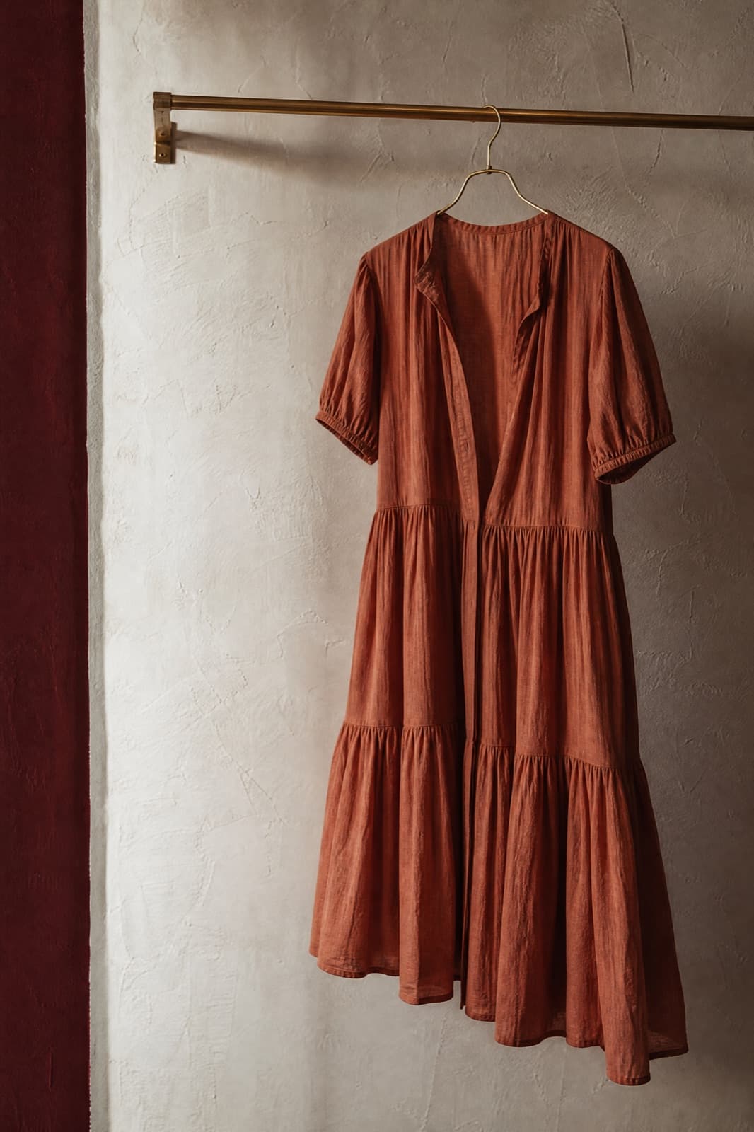 Tiered Cotton Dress, hung from a rail against limestone plaster.