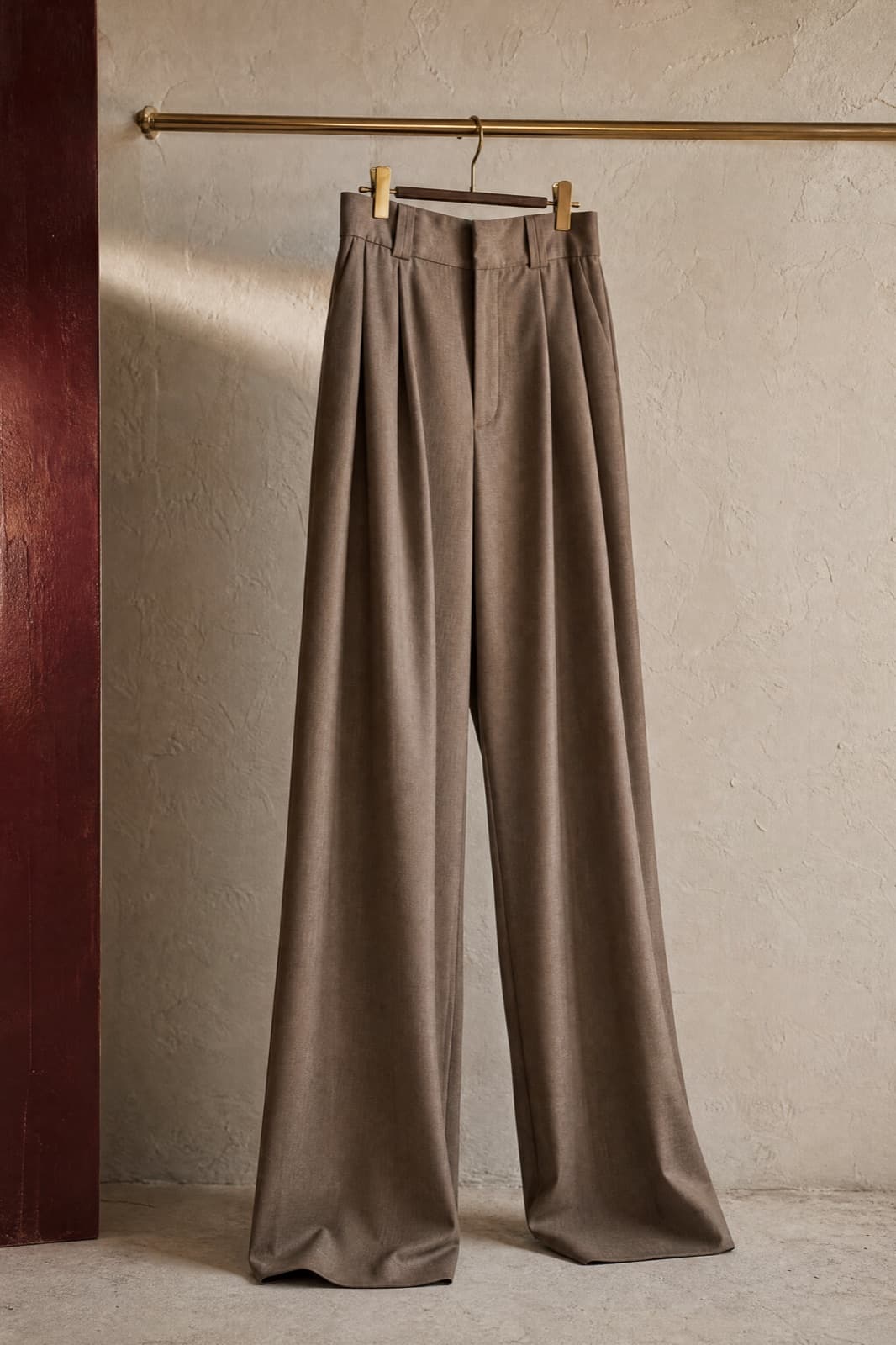 Wide-Leg Trouser, hung from a rail against limestone plaster.